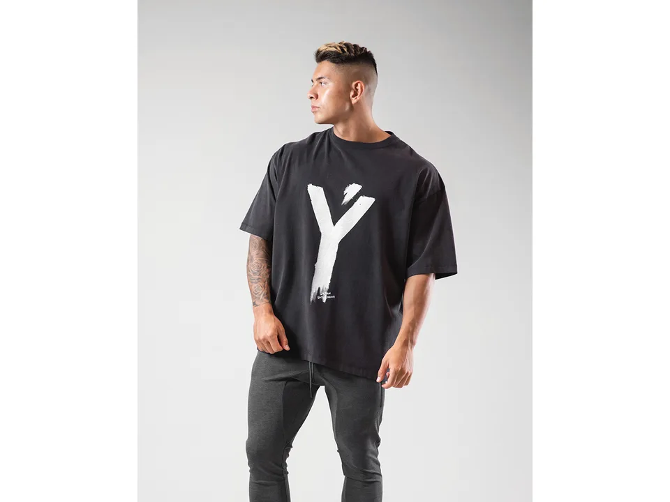 A man wearing an oversized black t-shirt with a large white graphic print.