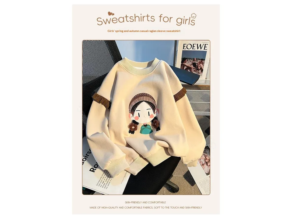 Full view of the beige girls' sweatshirt with a cartoon graphic and brown ribbed sleeve details.