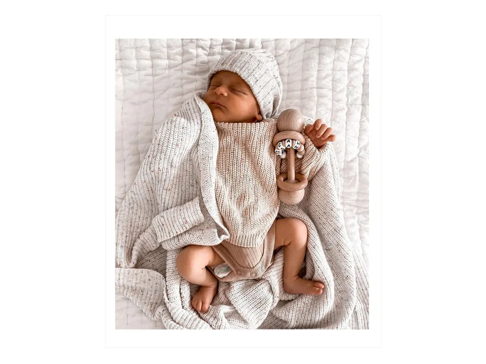 A baby sleeping while wearing the knitted sweater and matching hat.
