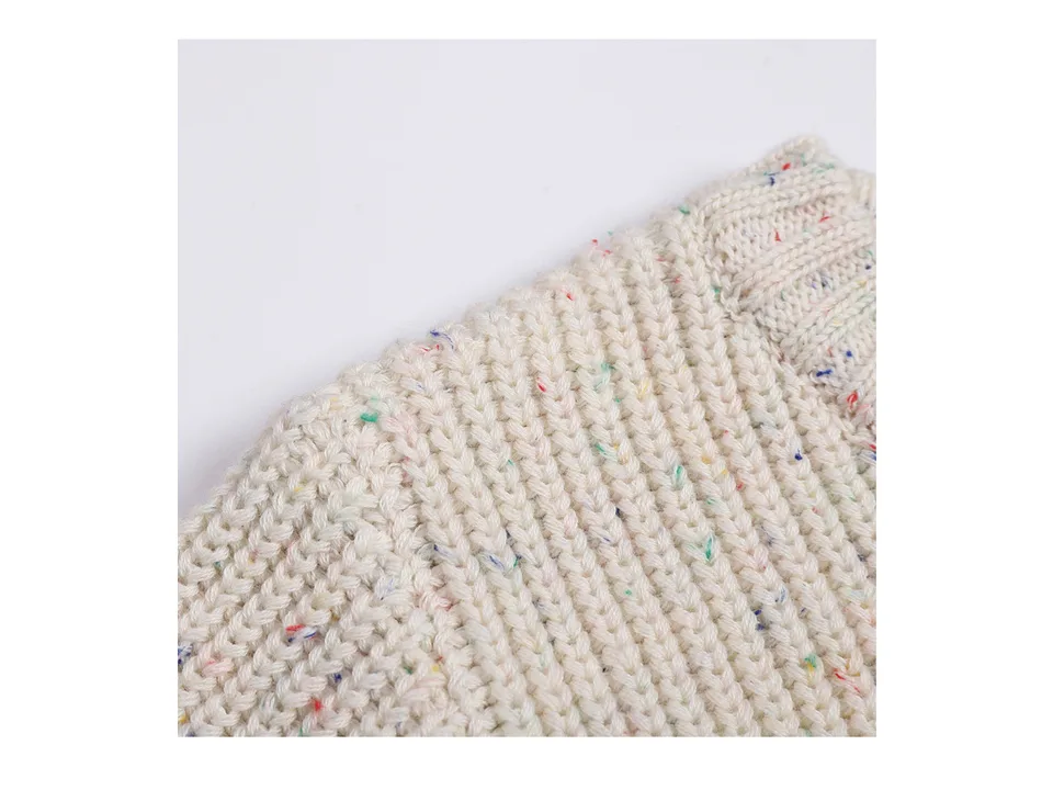 Close-up of the beige knitted sweater fabric with colorful flecks.