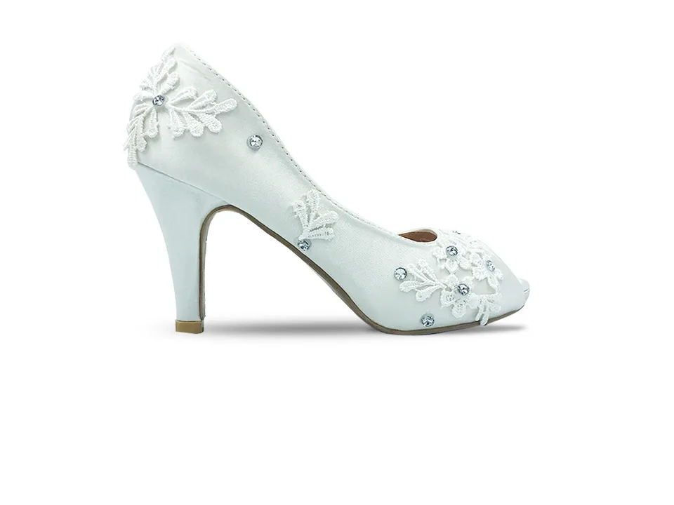 Side view of a white lace stiletto pump with rhinestone embellishments.