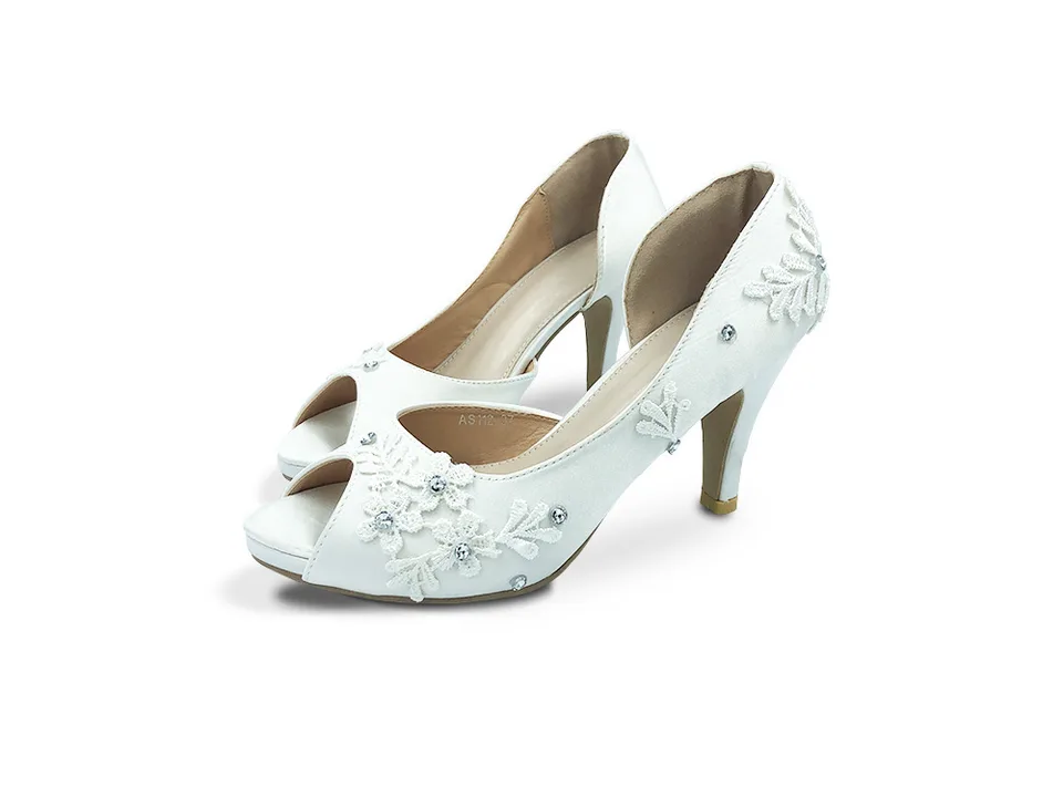 Pair of white lace wedding pumps with open toes and rhinestone details.