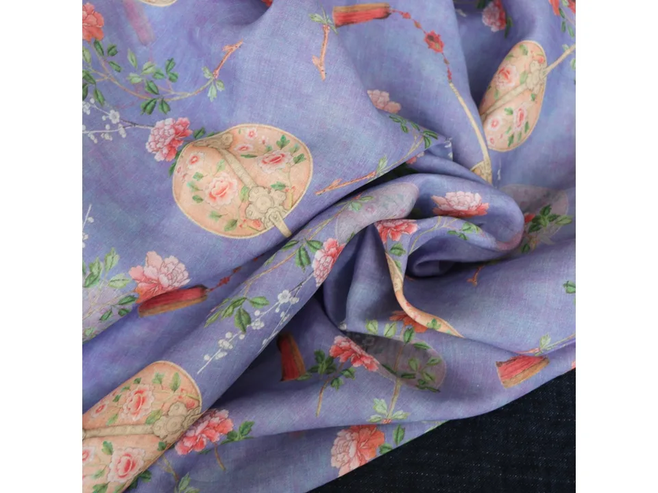 Close-up of purple ramie fabric with floral and fan print, showing texture and drape.
