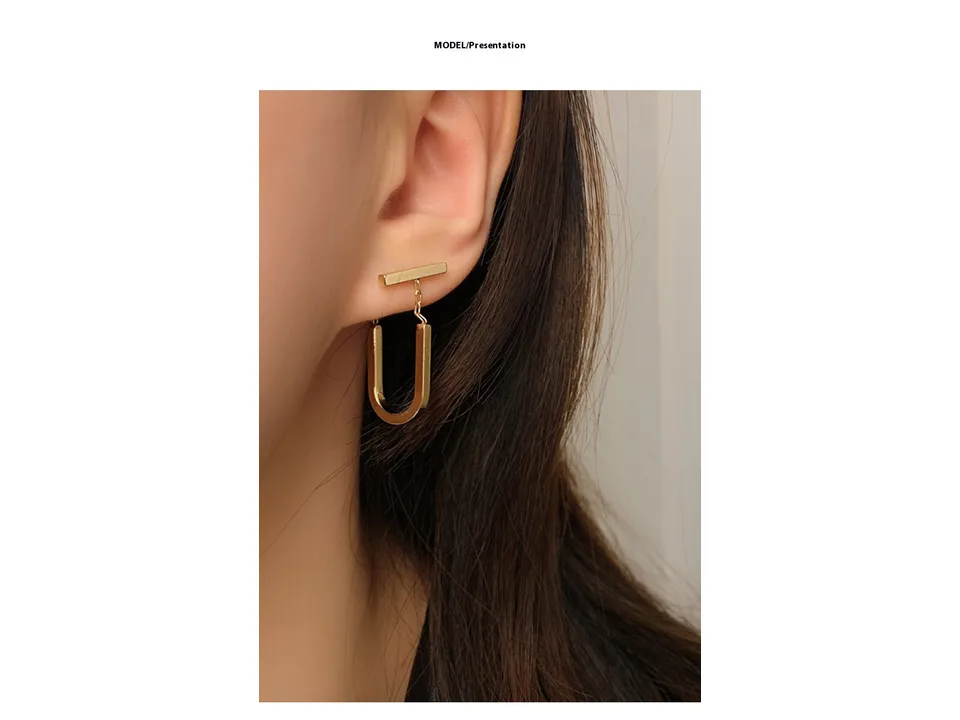 A close-up view of a gold U-shaped drop earring worn on an ear.
