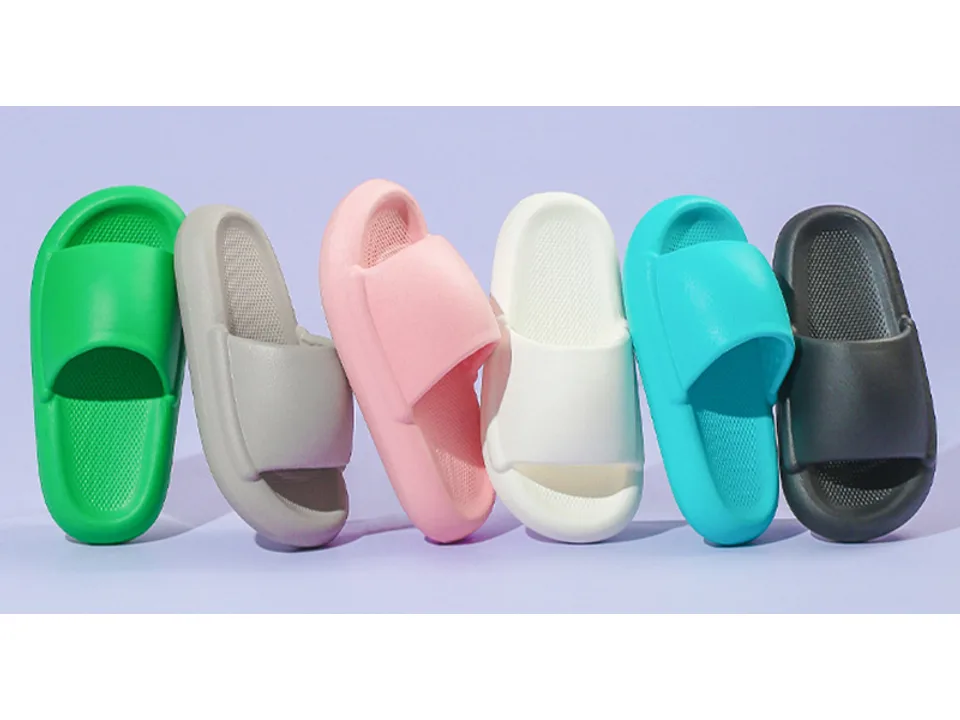 A row of thick-soled EVA slippers in green, grey, pink, white, blue, and black.