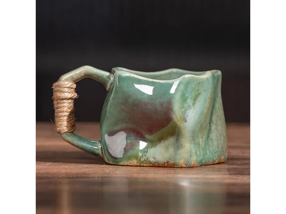 A green irregular ceramic mug with a rope-wrapped handle.