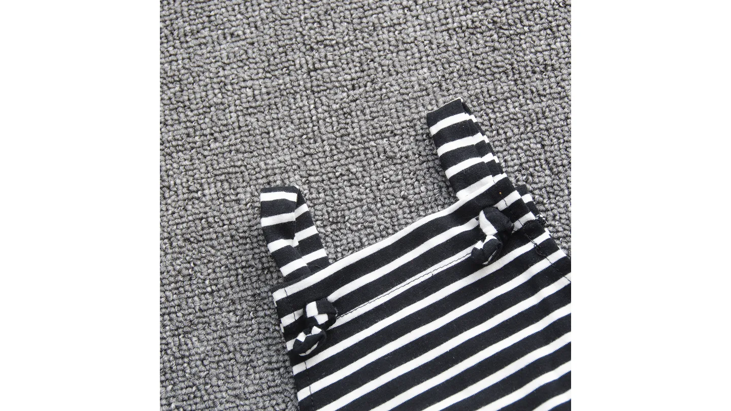 Close-up of the black and white striped fabric and shoulder strap detail of the baby romper.