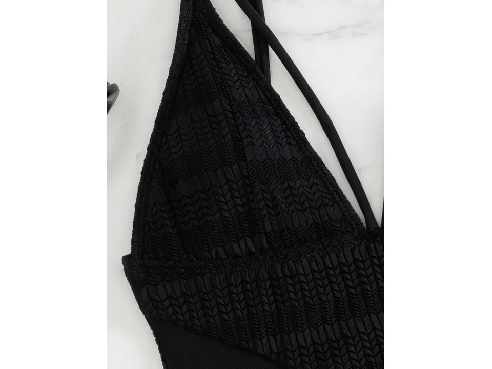 Close-up of the textured fabric and strap detail on the black swimsuit.