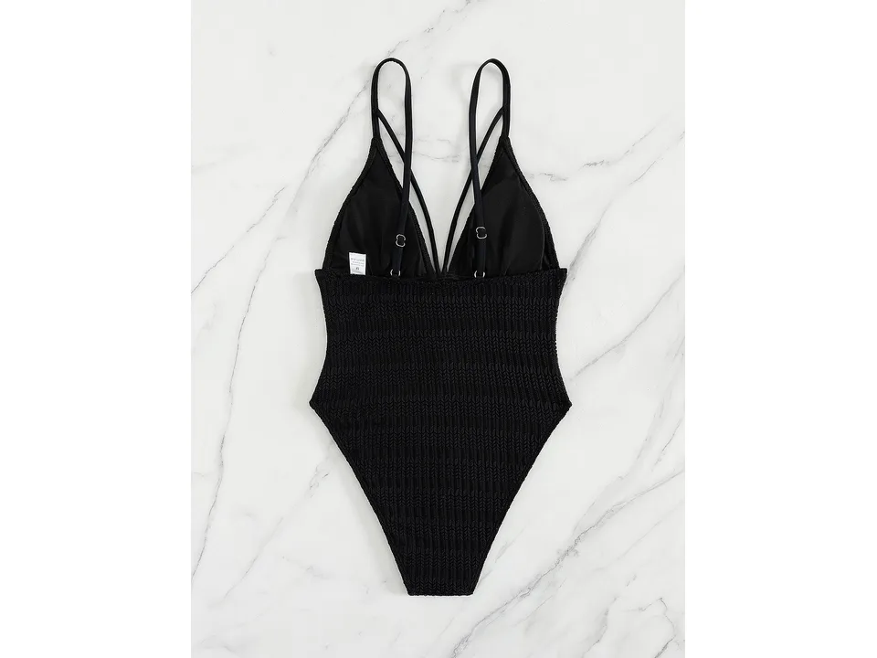 Back view of the black one-piece swimsuit on a marble background.