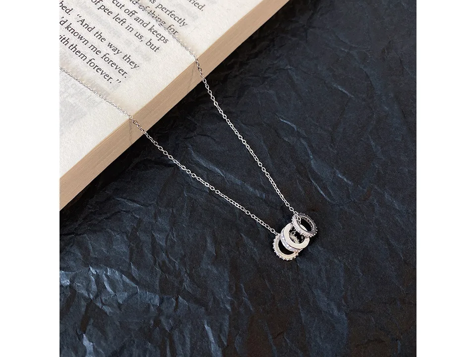 Close-up of the silver multi-layer ring pendant necklace resting on a book.