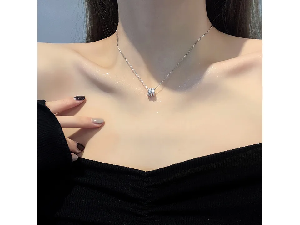 A woman wearing a silver multi-layer ring pendant necklace.