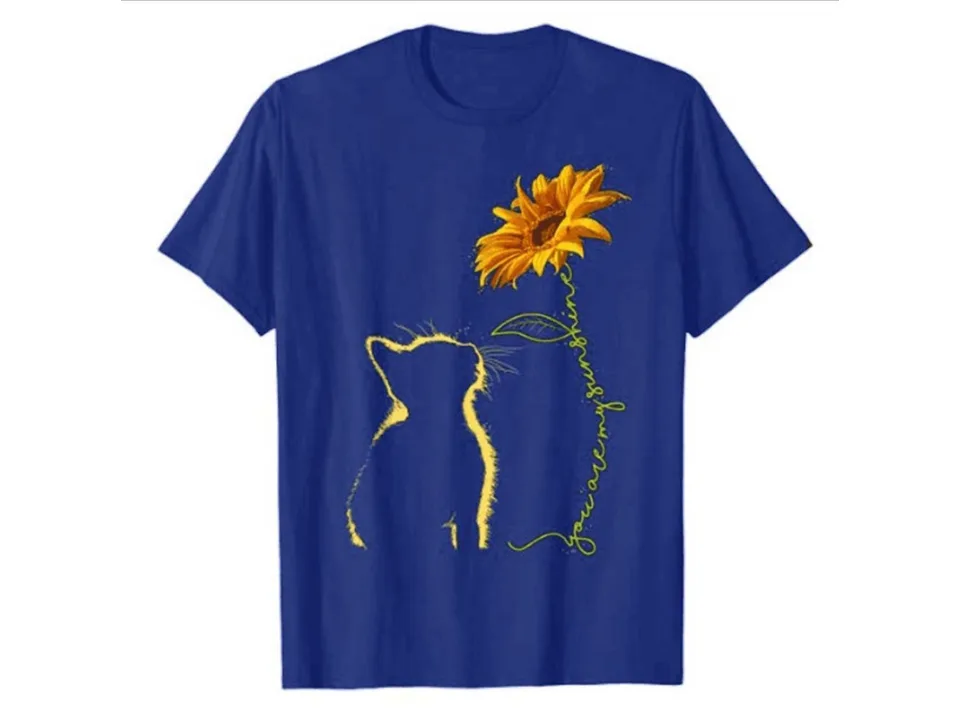 A blue t-shirt featuring a graphic of a cat looking at a sunflower with the text 'you are my sunshine'.