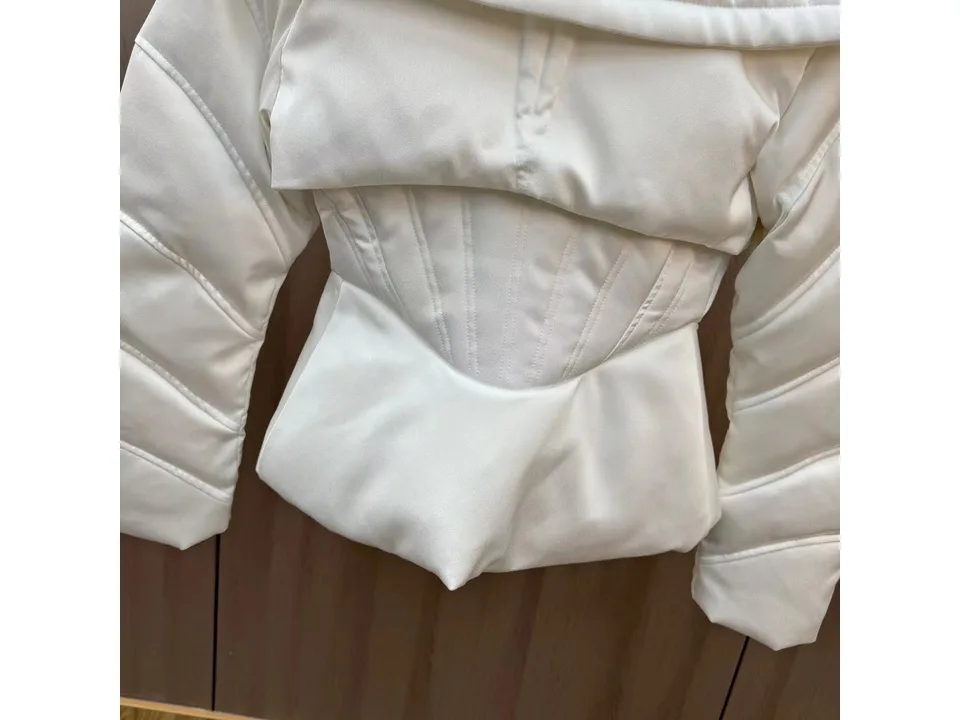 Close-up of the white jacket's corset-style waist and quilted fabric.