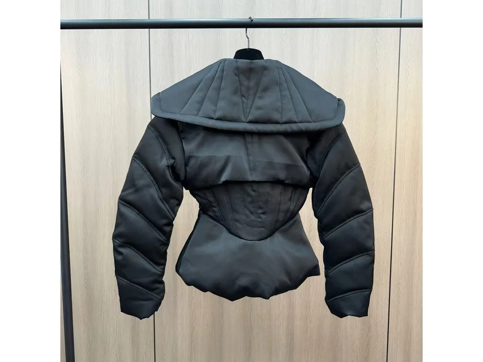 Full back view of the black jacket hanging on a rack, showing the wide collar and corset waist.