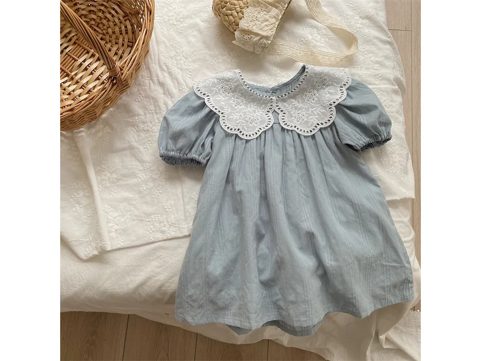 The light blue dress laid flat on a white fabric surface.
