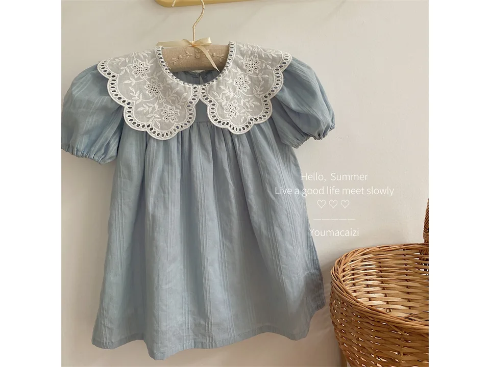 A light blue girls' dress with a white embroidered lace collar hanging on a hanger.