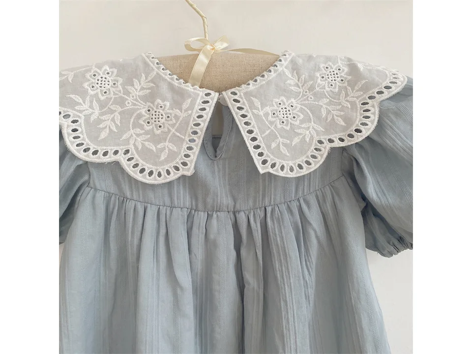 Close-up of the white embroidered lace collar on the light blue dress.