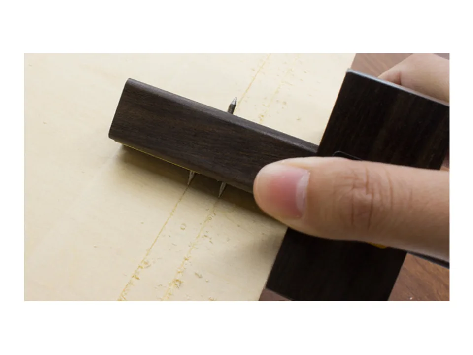 Close-up of dual pins on a marking gauge scribing lines into wood