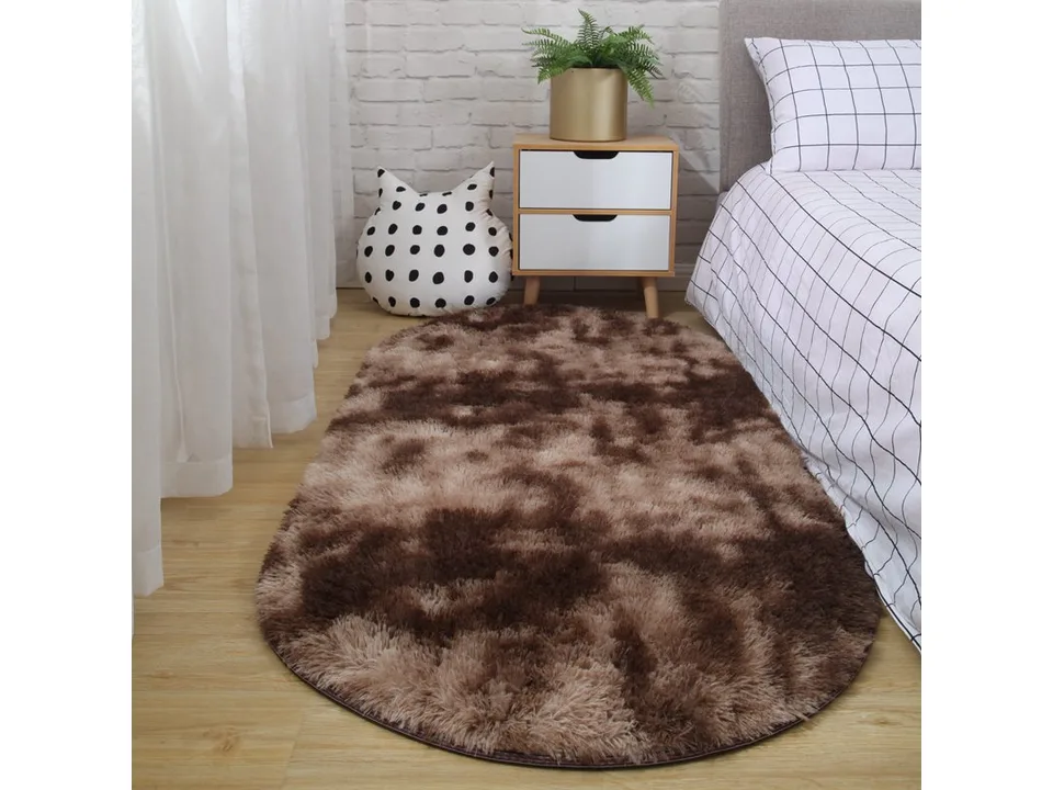 A dark brown oval shaggy rug placed on a wooden floor next to a bed.