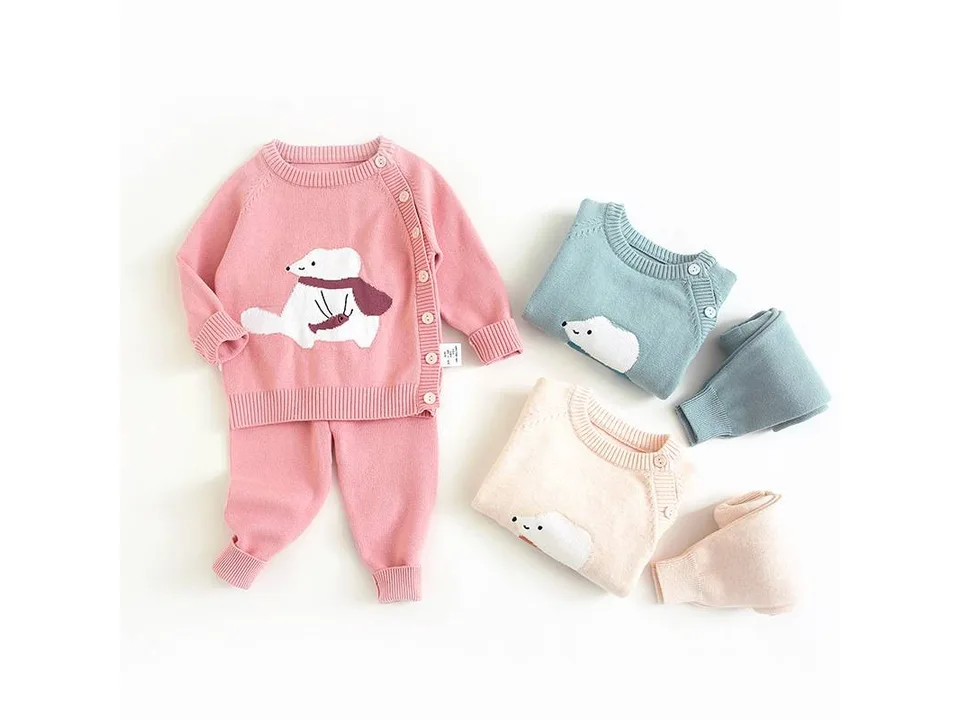Infant knitted sweater and pants set in pink, blue, and beige with a polar bear design.
