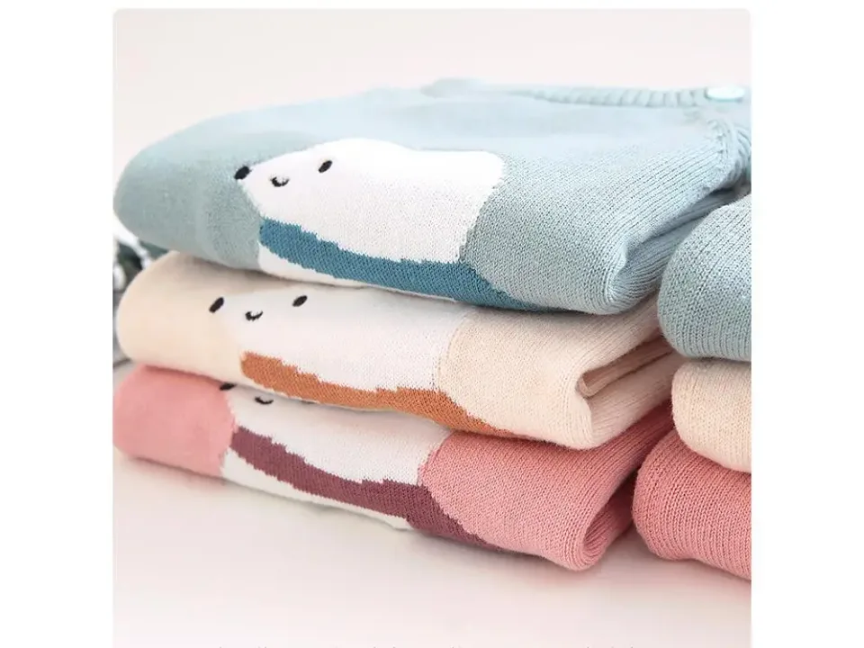 Close-up of folded knitted sweaters showing the polar bear pattern and fabric texture.