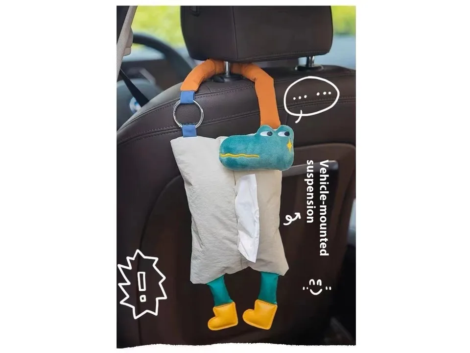 Green crocodile plush tissue holder hanging from a car headrest.