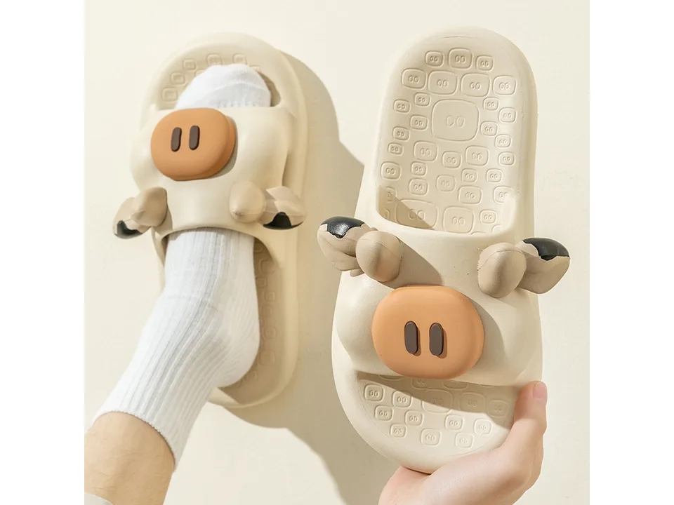 A person wearing a white cow slipper on one foot and holding another in their hand.