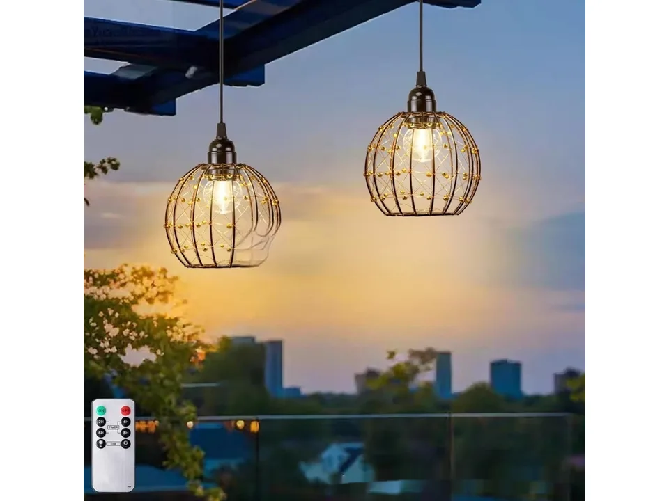 Two pendant lights hanging outdoors at dusk.