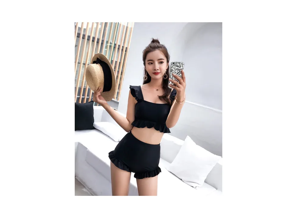 A woman wearing a black high-waisted ruffle bikini set, front view.