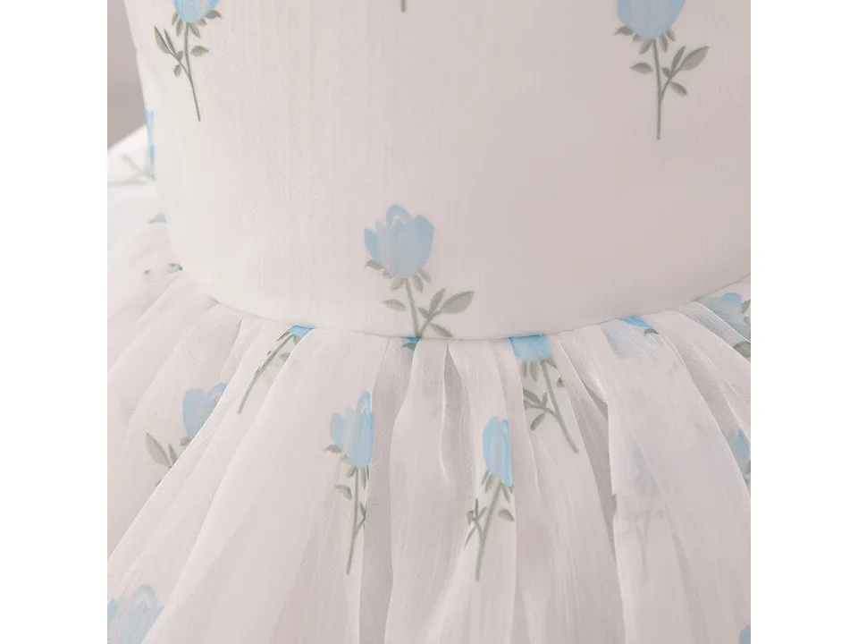 Close-up of the white fabric with blue floral print and gathered skirt detail.