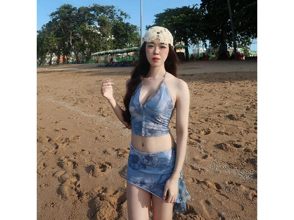 A woman wearing a blue floral halterneck top and matching mini skirt on a beach.