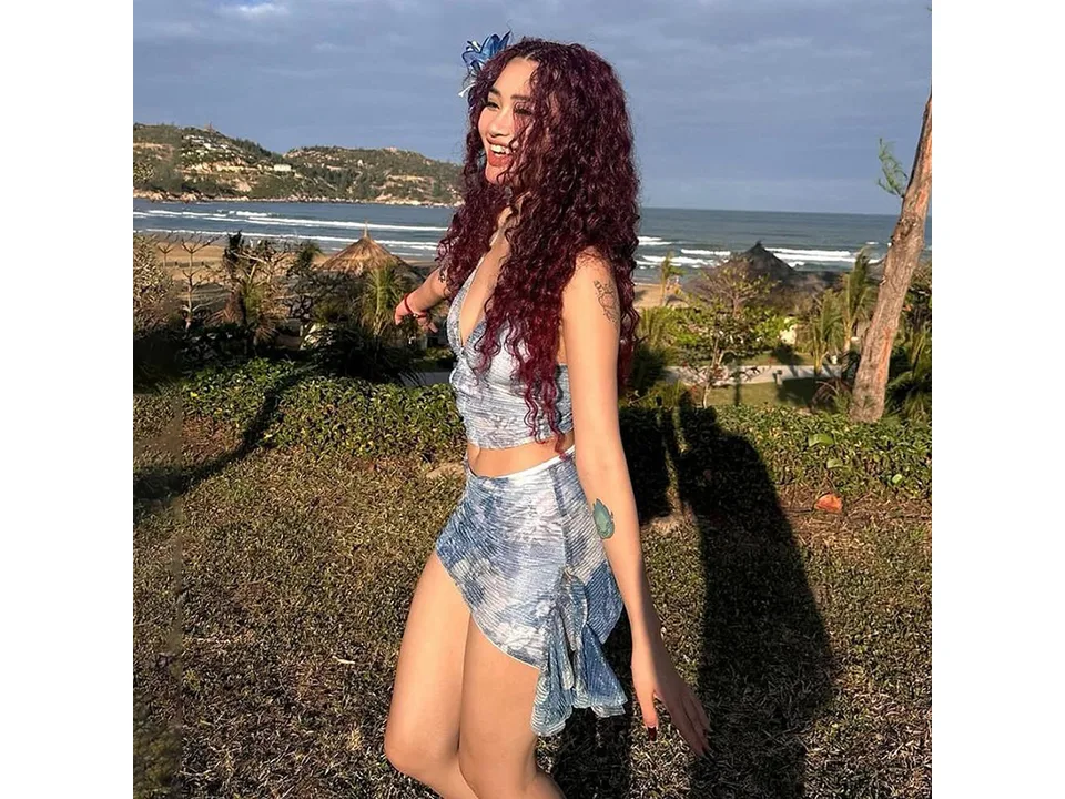 A woman with curly hair wearing a blue floral two-piece set outdoors.
