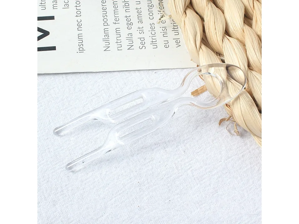 A single clear plastic U-shaped hair fork on a white surface.