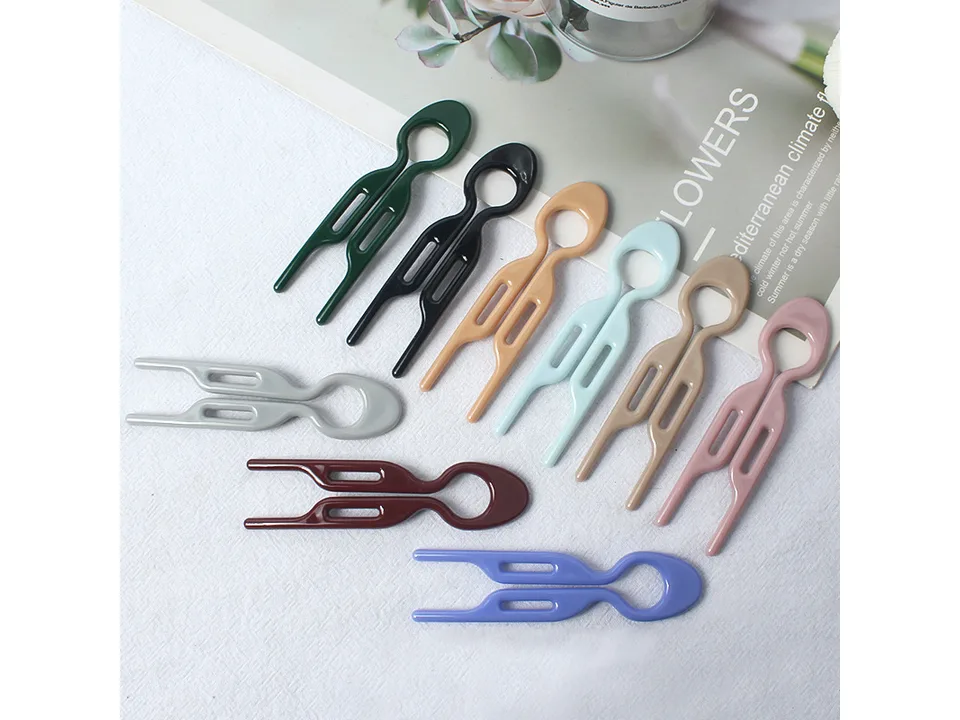 A collection of U-shaped hair forks in various colors arranged on a white surface.