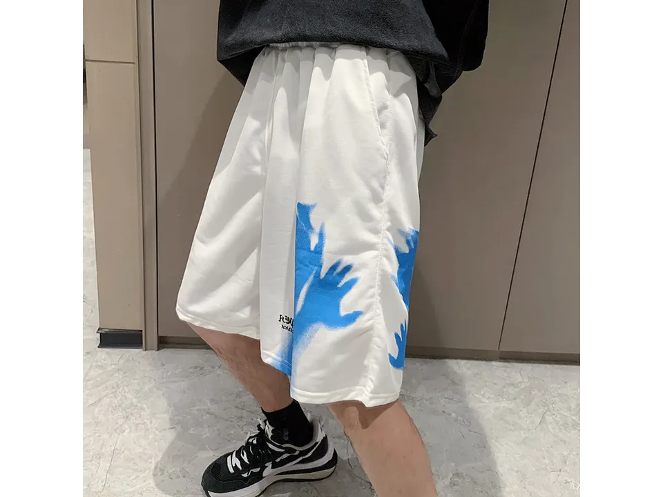 A person wearing white shorts with a blue hand graphic.