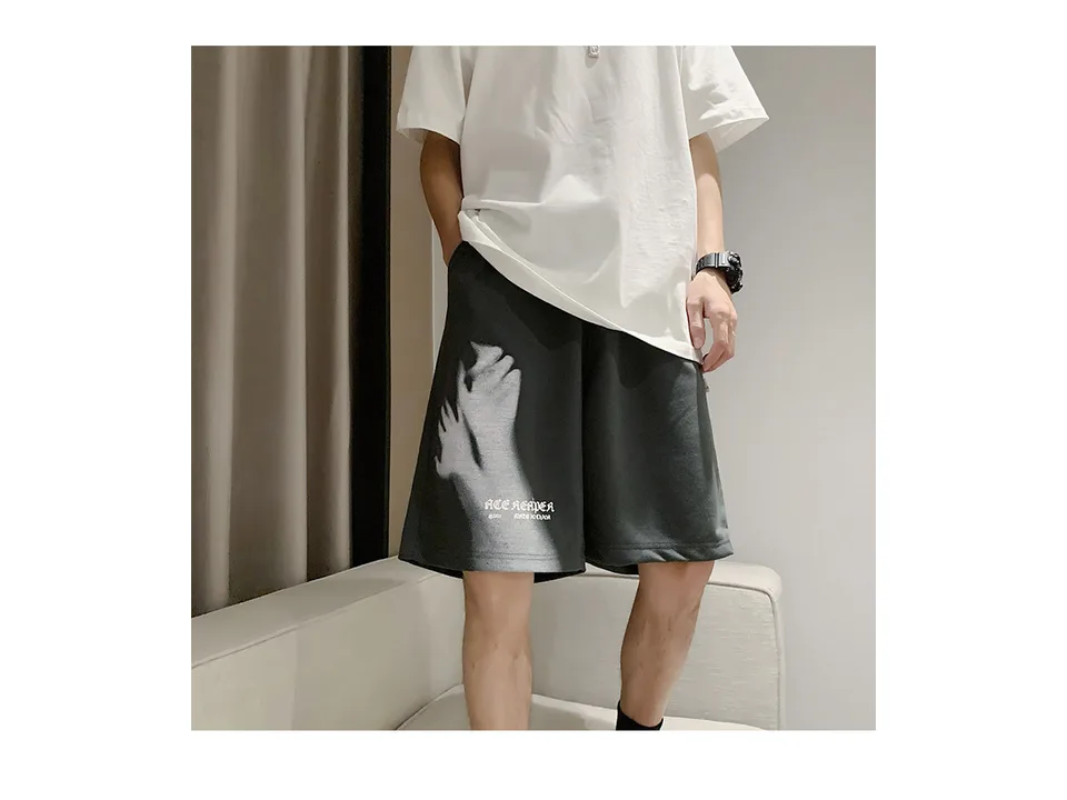 A person wearing dark grey shorts with a white hand graphic.
