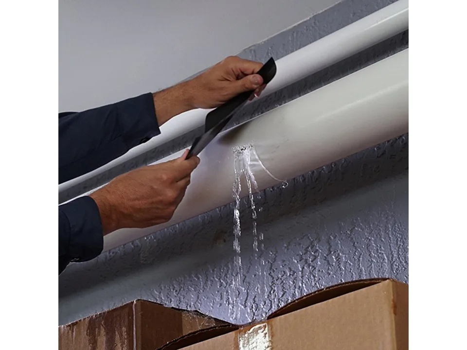 Hands applying adhesive tape to a leaking pipe.