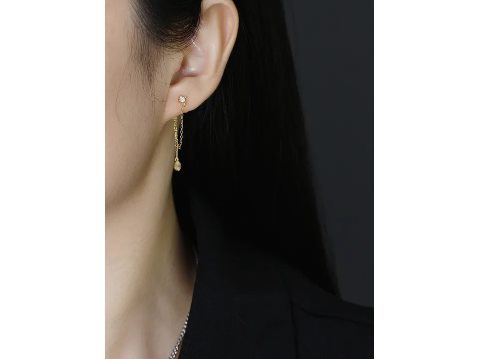 A close-up of a person wearing the gold chain earring.