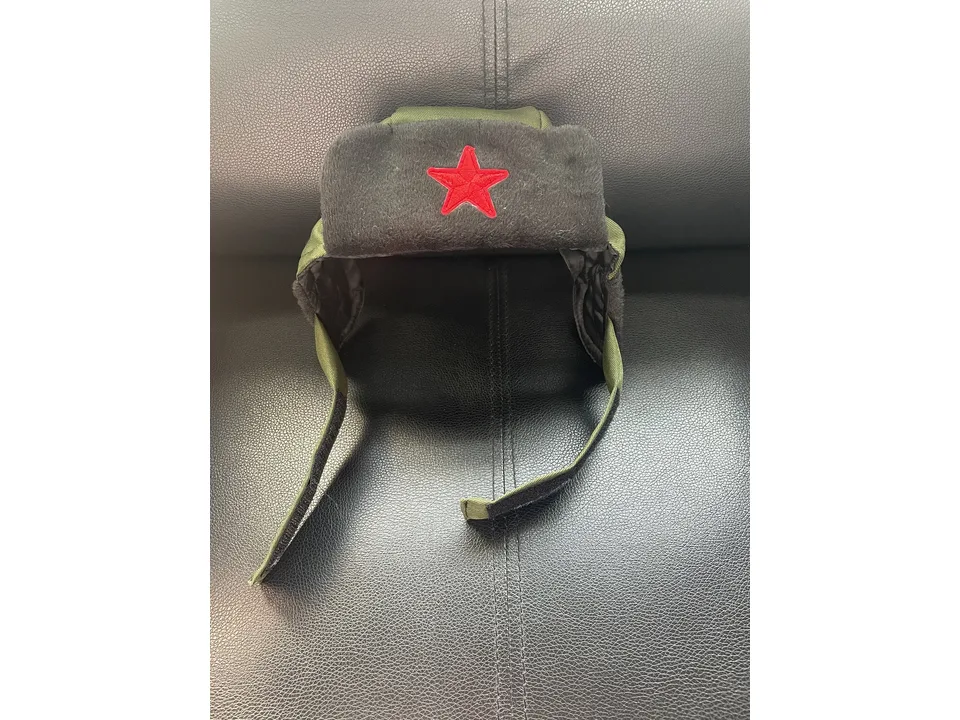 A close-up of the green and black trapper hat with a red star emblem.