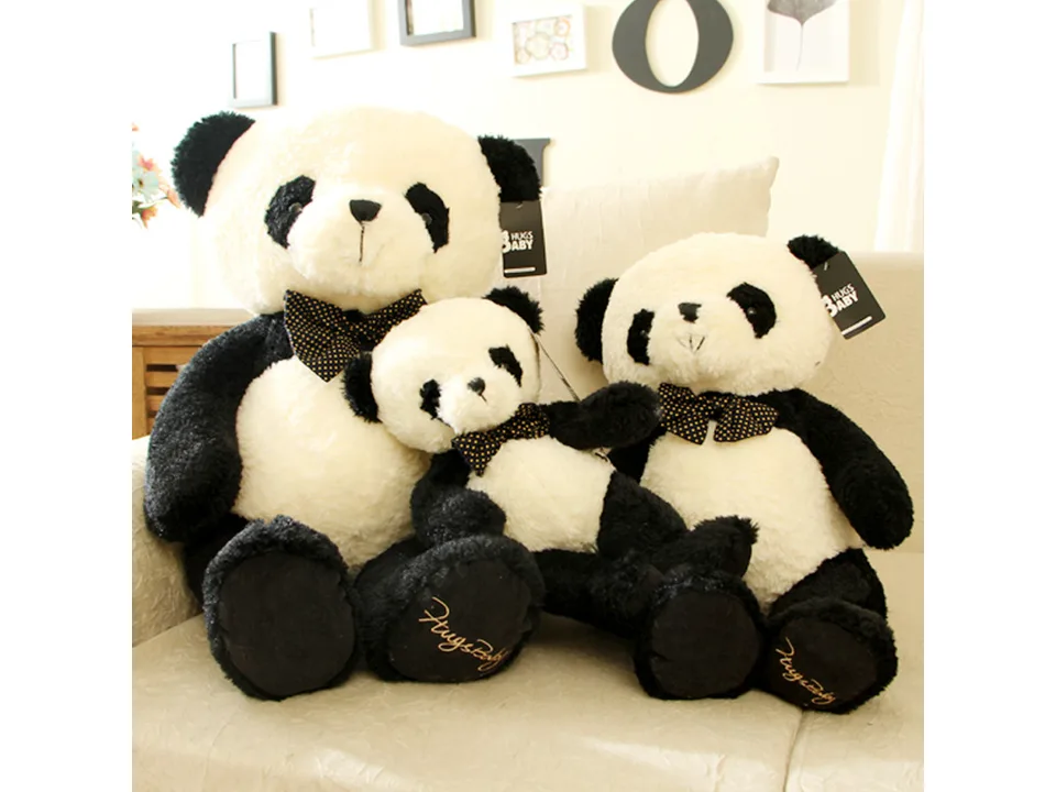 Three plush panda toys of different sizes sitting on a sofa.