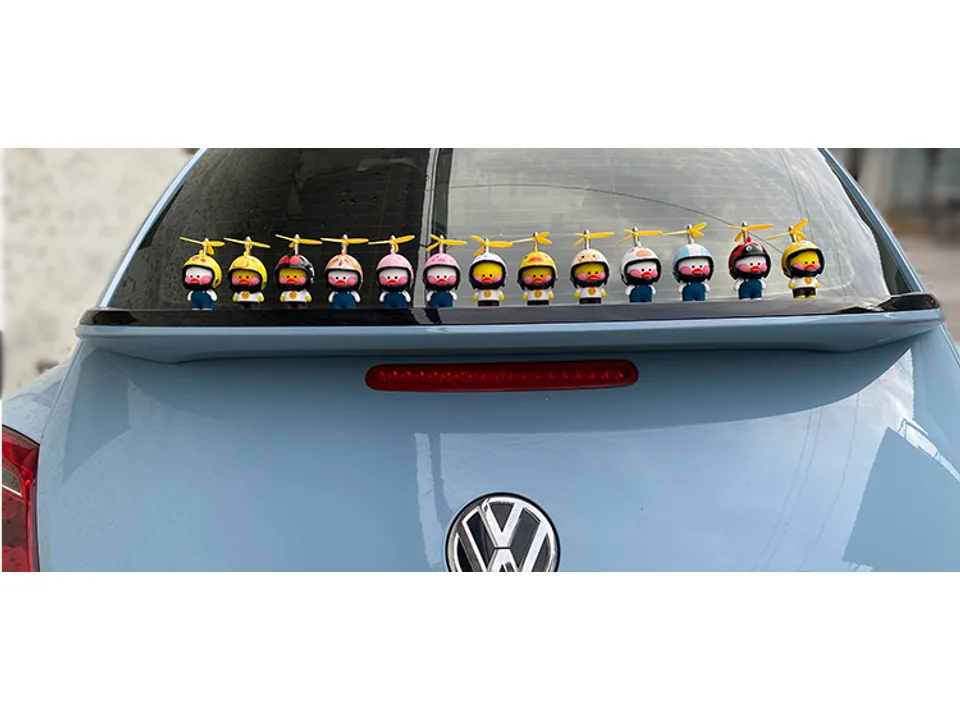 A collection of cartoon duck ornaments with different helmets and propellers on a car dashboard.