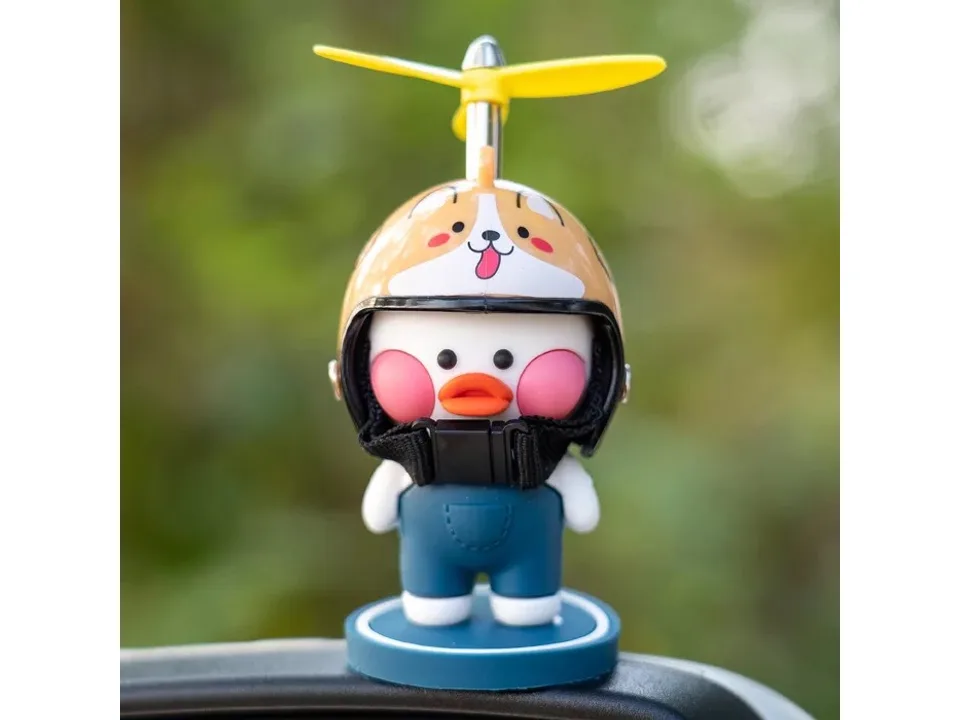 A row of cartoon duck ornaments with helmets and propellers lined up on the rear shelf of a car.