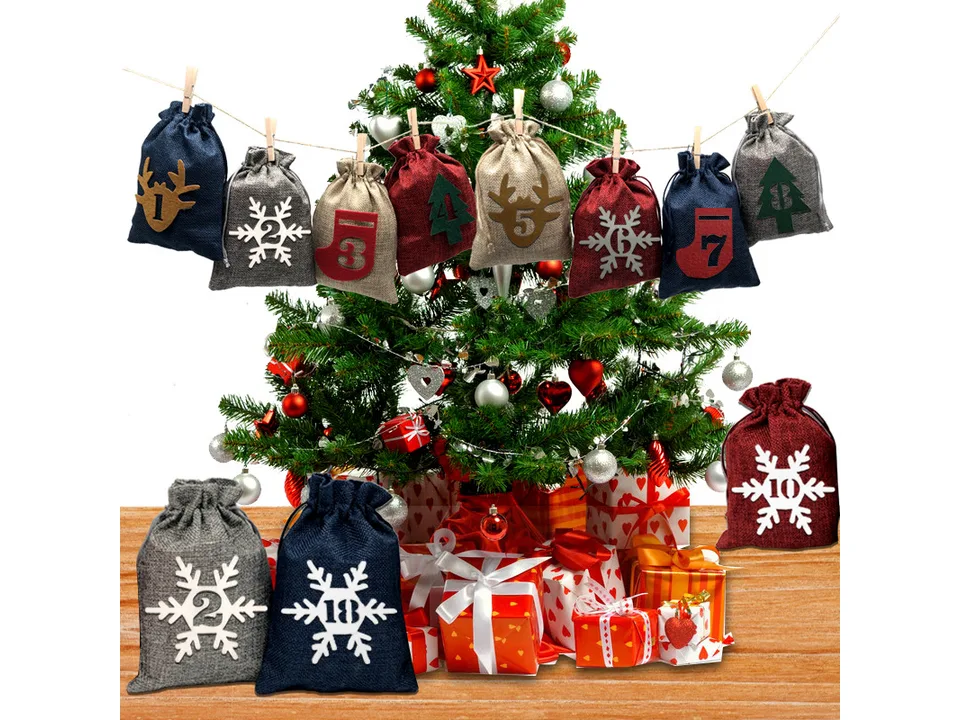 Christmas advent calendar bags hanging on a string in front of a Christmas tree.