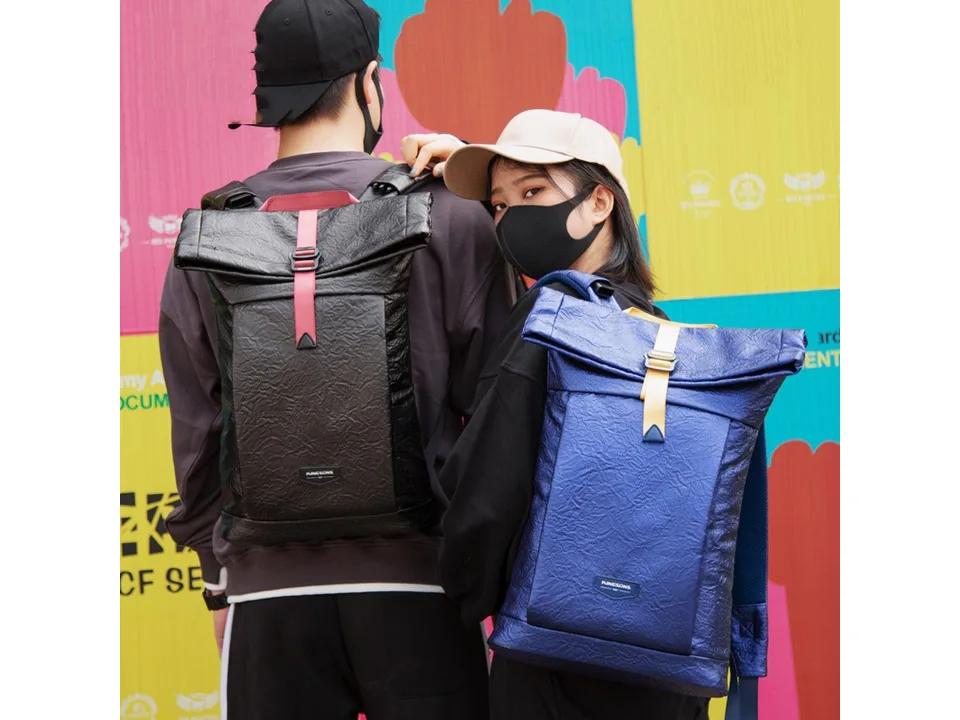 Two people wearing different colored roll-top backpacks.