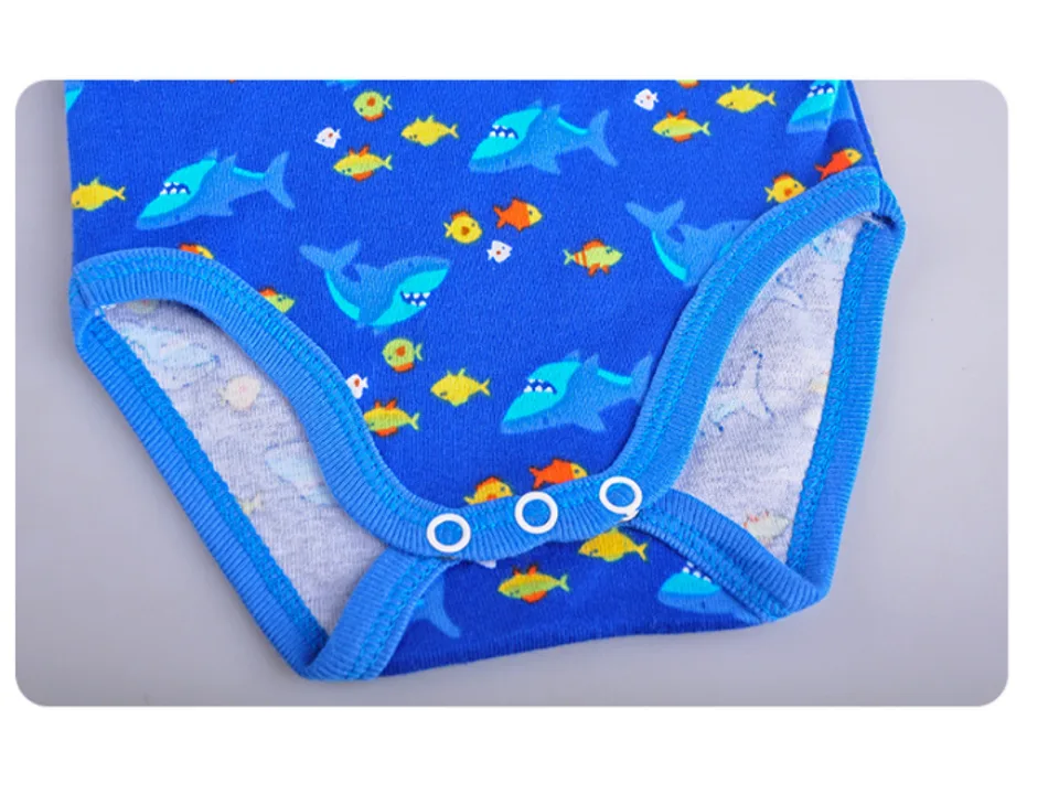 Close-up of the bottom of a blue baby bodysuit with a shark and fish pattern.