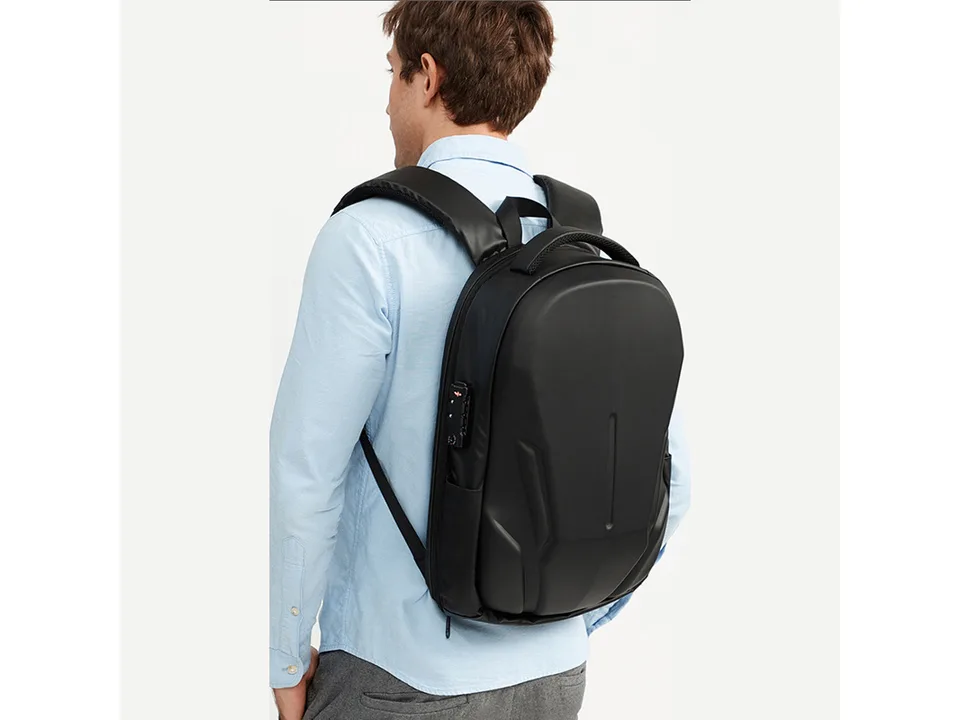 A man wearing the black hard shell backpack.