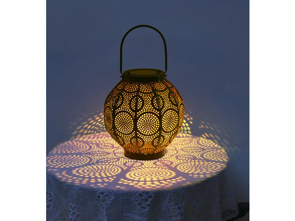 A decorative metal lantern glowing on a table, casting a patterned light shadow.