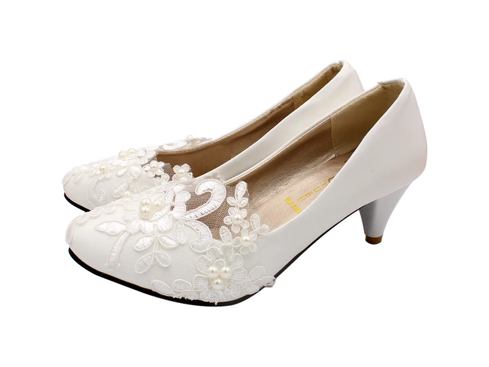 Side view of white lace wedding shoes with a small heel.