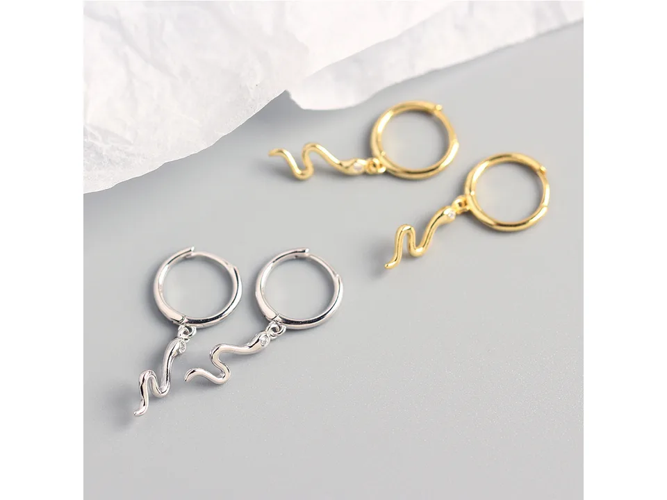A pair of gold and a pair of silver snake hoop earrings.