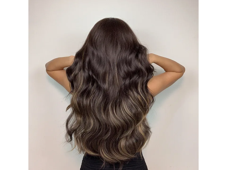 Back view of a woman with long, wavy dark brown hair with highlights.